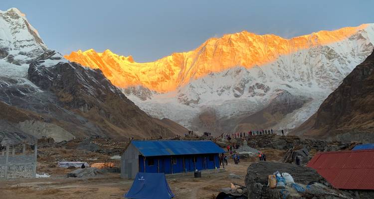Sunset light on mountains with huts and tents in foreground.