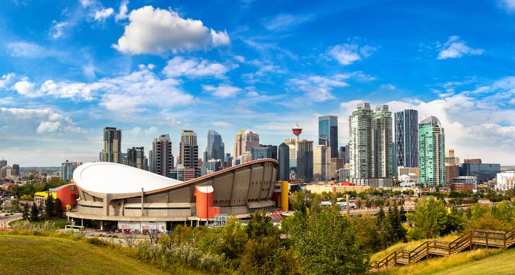 Panorama van de skyline van Calgary met de Saddledome onder een heldere blauwe hemel.