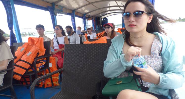 Grupo de turistas sentados en un bote con chalecos salvavidas y vista escénica del río.