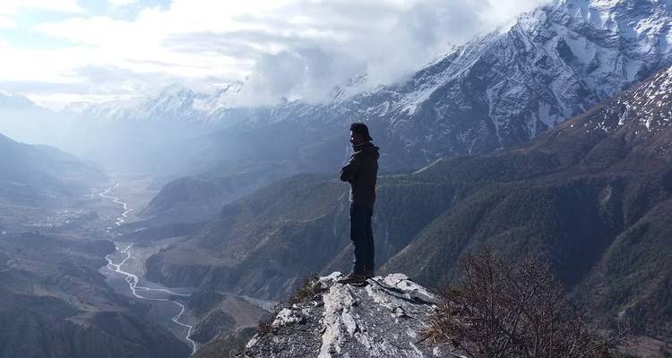 Person, die am Rand einer Klippe steht mit Blick auf Berge und Tal.