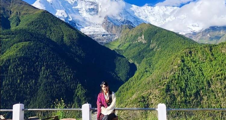 Person, die mit einer atemberaubenden Berglandschaft im Hintergrund sitzt.