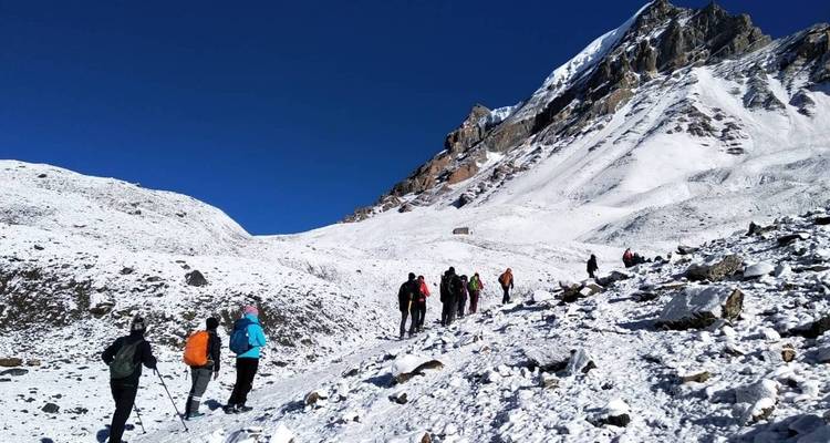 Wanderer, die durch schneebedecktes Berggelände laufen.