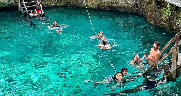 Des personnes qui nagent dans un cénote aux eaux claires.