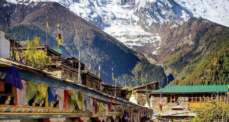 Traditionelles Dorf mit Bergen im Hintergrund und Gebetsfahnen.