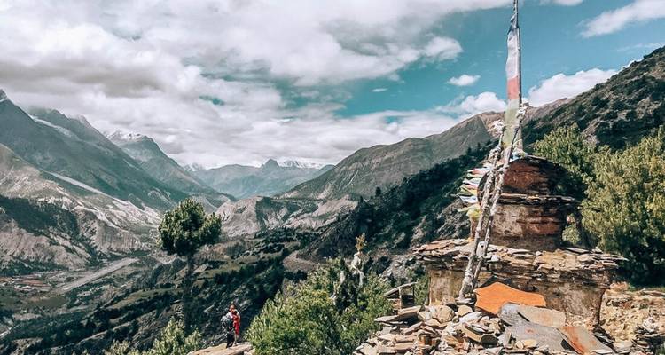 Person mit Gebetsfahnen und Bergen im Hintergrund.