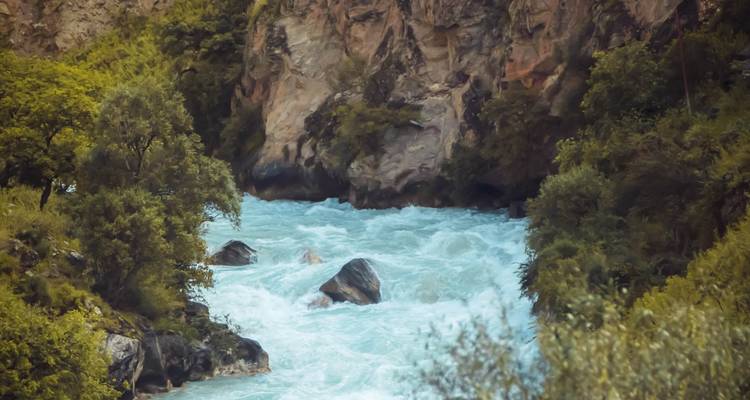 Een snelstromende turquoise rivier die door een rotsachtige kloof snijdt.