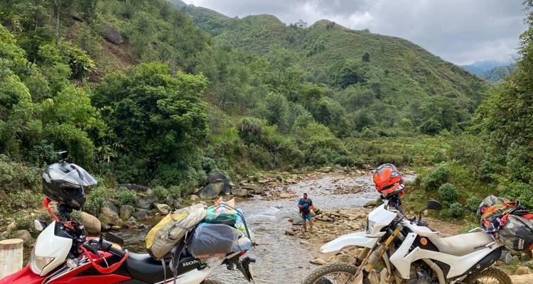 Motorfietsen geparkeerd bij een beek met een persoon.