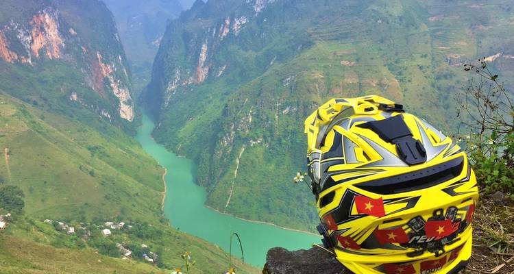 Ein Helm mit leuchtenden Farben und vietnamesischen Flaggen mit Blick auf ein Flusstal.