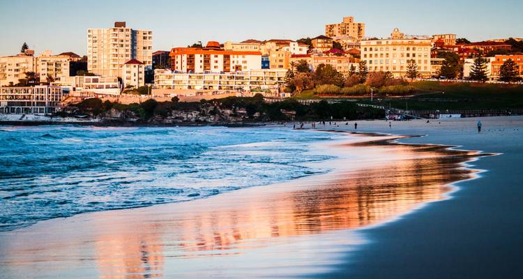 Plage de Bondi au coucher du soleil avec la ville en arrière-plan.