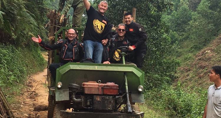 Gruppe von Menschen auf einem kleinen offenen Fahrzeug in einer üppig grünen Gegend.