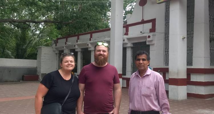 Zwei Personen posieren vor einem schlichten historischen Gebäude.