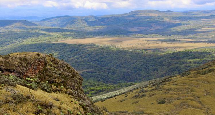 Large vue panoramique sur les hautes terres boisées et les landes ouvertes sous un ciel partiellement nuageux au Kenya.