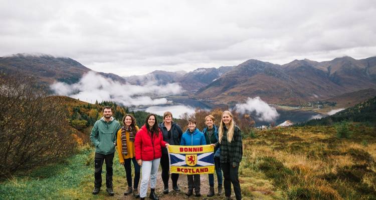 Grupo en paisaje escénico sosteniendo una bandera escocesa.