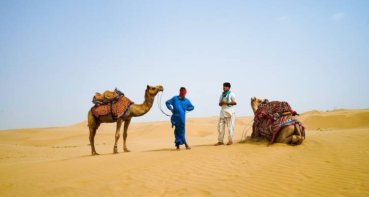 Two men with camels in a desert environment.