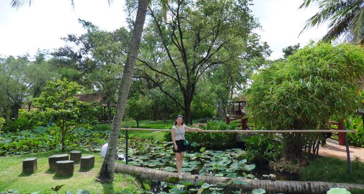 Een persoon die een kleine brug oversteekt in een weelderige tuinomgeving.