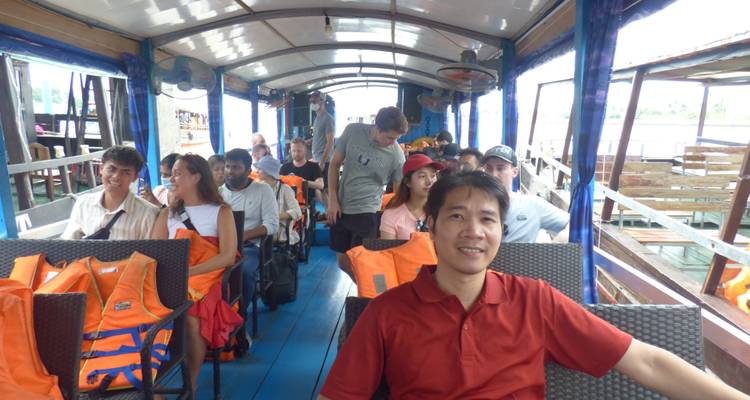 Passagiers gezeten in een boot met zichtbare reddingsvesten.