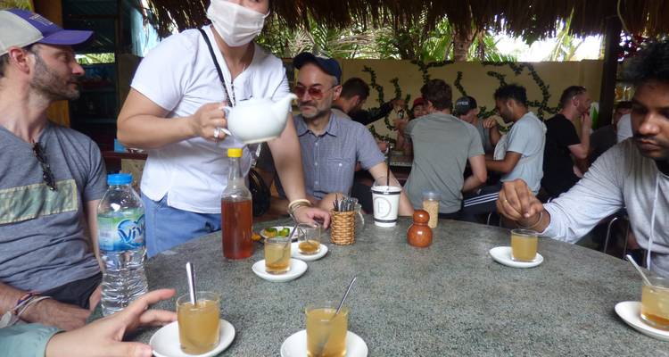 Mensen die rond een tafel zitten en genieten van thee of soortgelijke dranken.