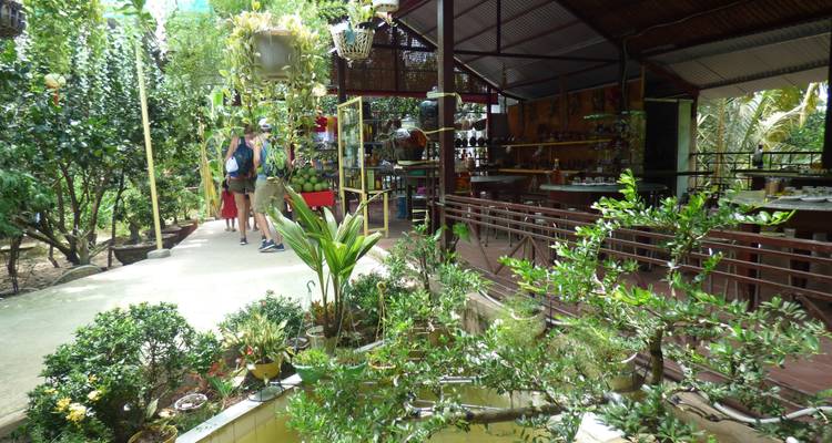 Menschen die een tuinachtig gebied met winkels en cafés verkennen.
