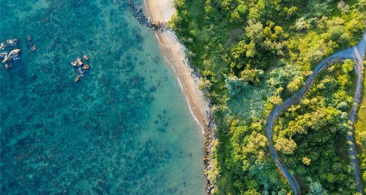 Aerial view of a coastal landscape with a road and beach.