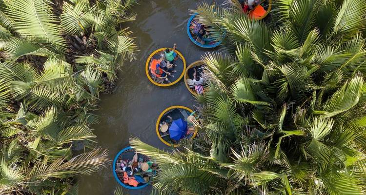 Aerial view of circular boats with people in a lush green canal.