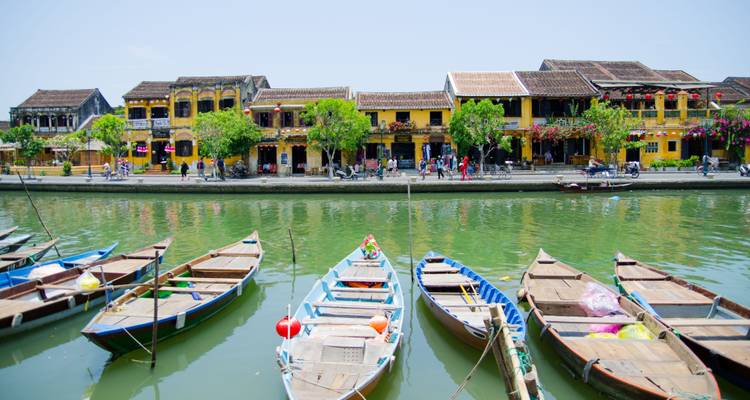 Traditional wooden boats docked in front of colorful historic buildings.