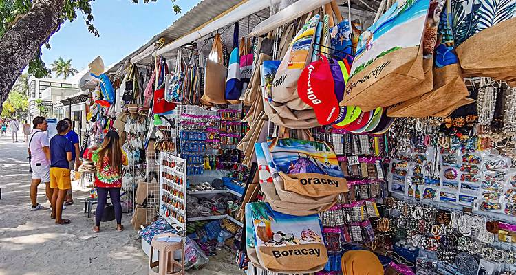 Puesto de mercado con recuerdos y bolsas en exhibición.