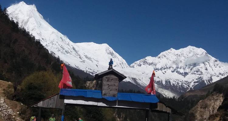 Mountain peaks with prayer flags and a blue sky.