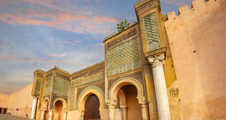 Historische poort met gedetailleerde mozaïekpatronen tijdens zonsondergang.