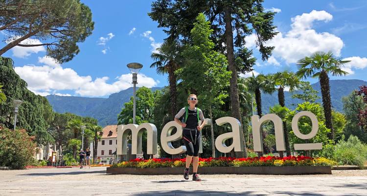 Personne debout devant le panneau de Merano sur une place.