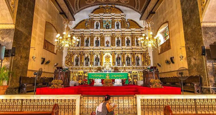 Altar ricamente decorado dentro de una iglesia con un visitante solitario.