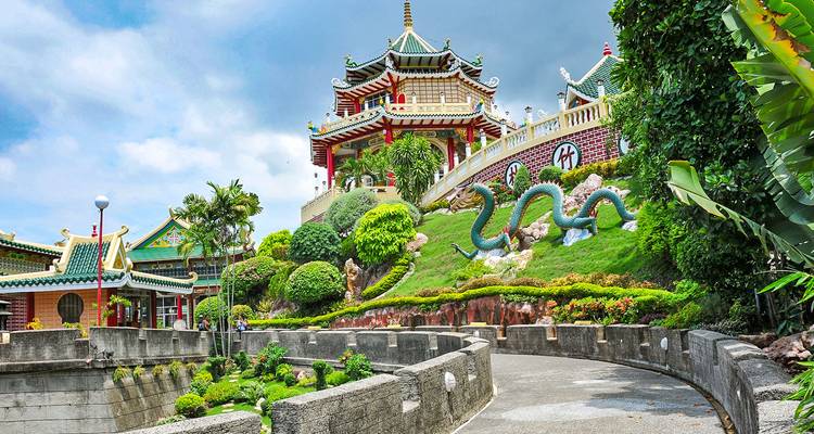Temple avec une architecture élaborée et une statue de dragon entourée de verdure.