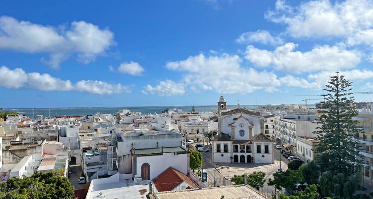 Paysage urbain avec des bâtiments blancs et une église visible.