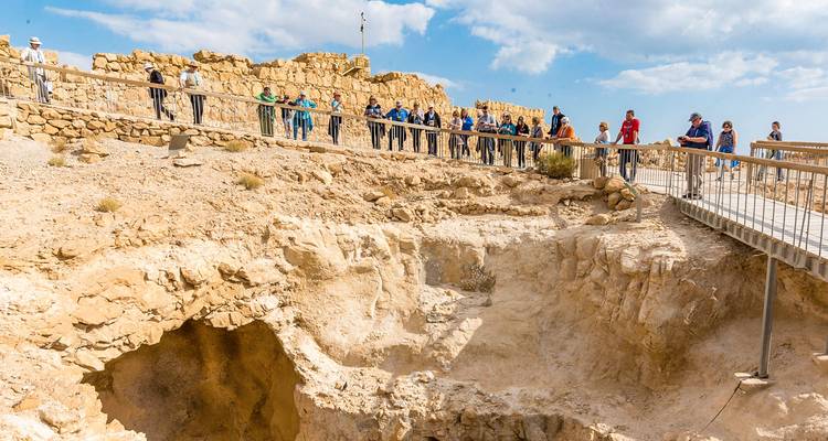 Groupe de touristes explorant des ruines archéologiques dans un paysage rocheux