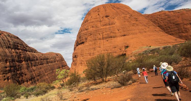 Bezoekers die wandelen door de rode rotsformaties van Uluru.