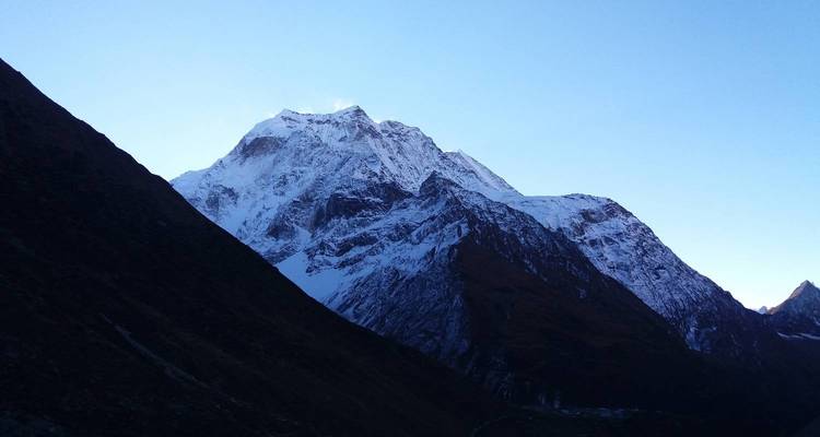 Bergsilhouette mit schneebedecktem Gipfel in der Dämmerung.
