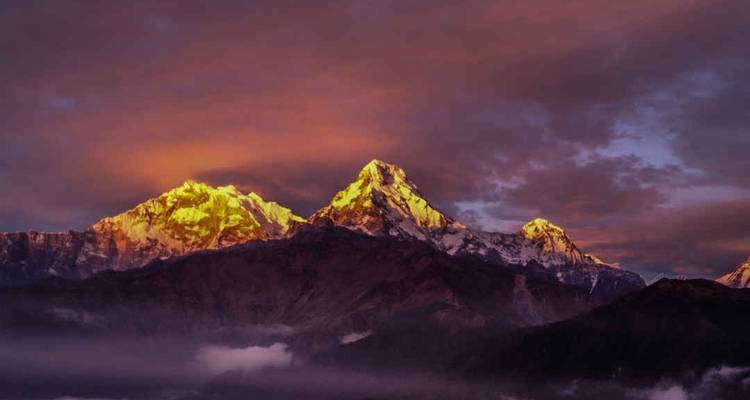 Majestätische Berggipfel bei Sonnenuntergang mit einem dramatischen Himmel.