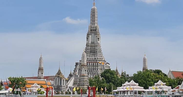 Tall temple spire with intricate designs and additional buildings on the grounds.