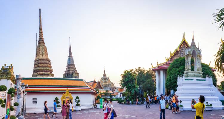 Tourists exploring a temple with multiple spires at sunset.