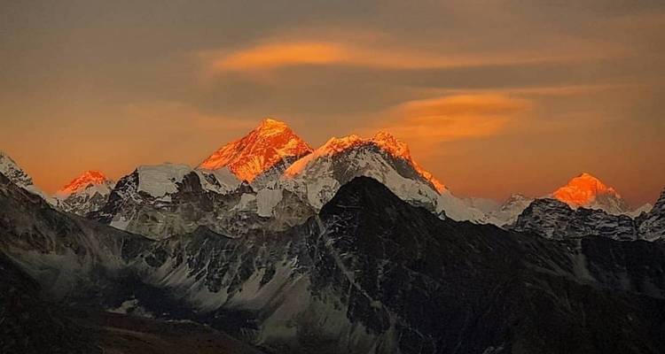 Majestuosa cordillera con picos que brillan en colores del atardecer.