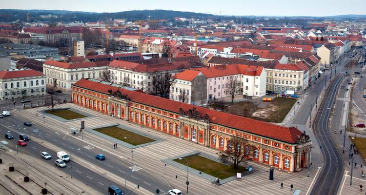 Vue aérienne d'une ville avec un long bâtiment historique au premier plan.