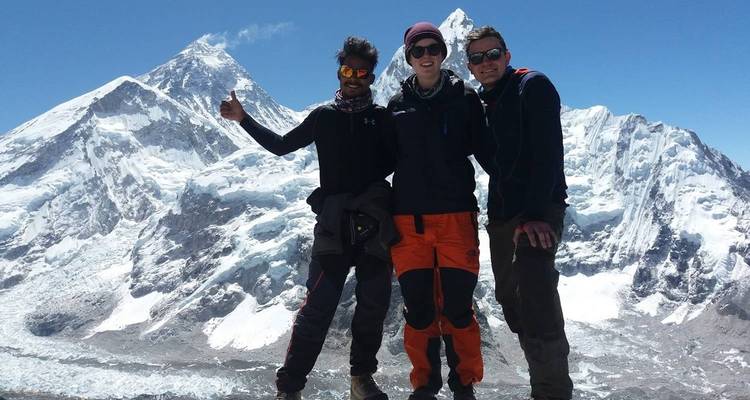 Drei Personen posieren vor schneebedeckten Berggipfeln.