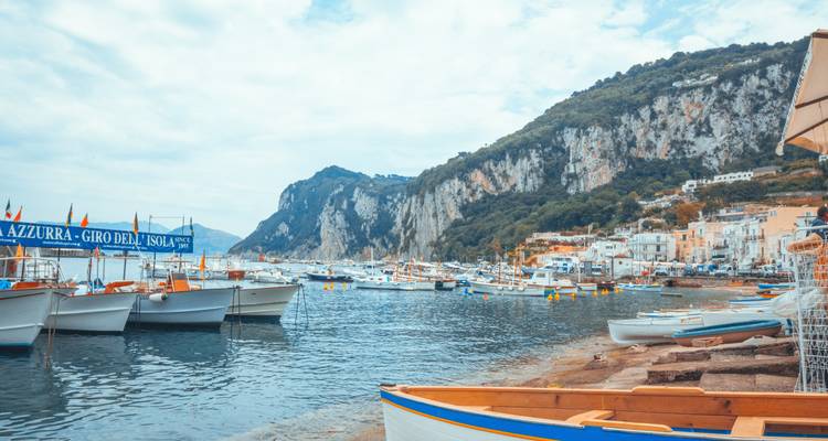 Vue côtière de Capri avec des bateaux et des falaises rocheuses.