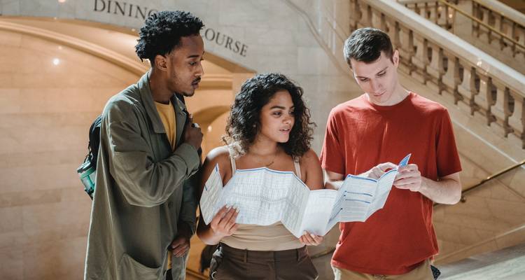 Drie mensen die naar een kaart kijken in een gebouw.