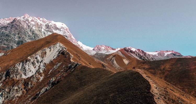 Wanderweg entlang schroffer Bergkämme unter klarem Himmel.