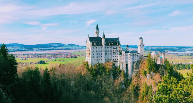 Schloss Neuschwanstein thront auf einem bewaldeten Hügel mit Panoramablick.