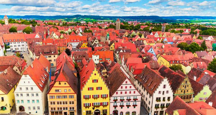 Luftaufnahme einer Stadt mit bunten Dächern und fernen Hügeln.