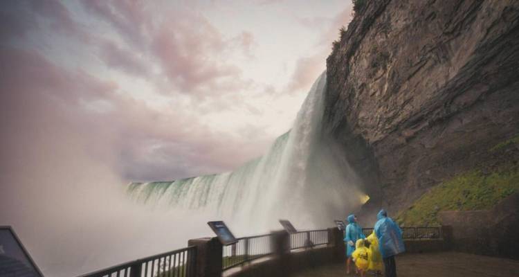 Les visiteurs vêtus de ponchos se tiennent près du rideau rugissant des chutes du Niagara enveloppés dans la brume.