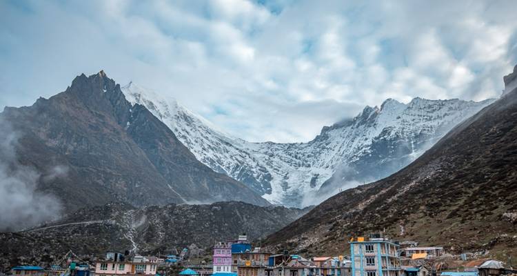 Cloud-covered mountains with a village below.