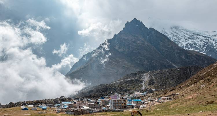 Dorf inmitten hoher Berge mit Wolken.