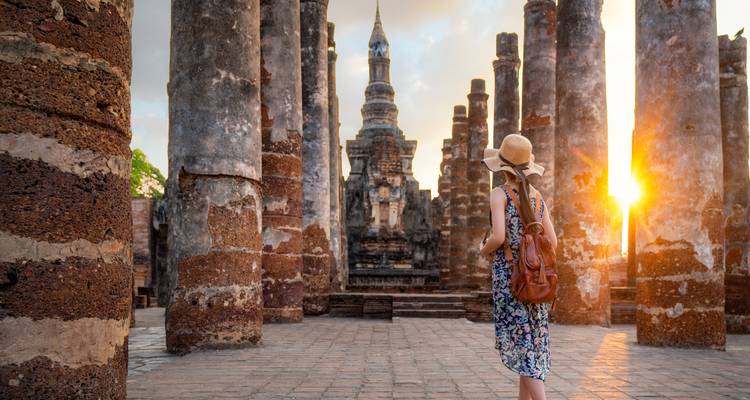 A visitor admiring historical ruins at sunset.